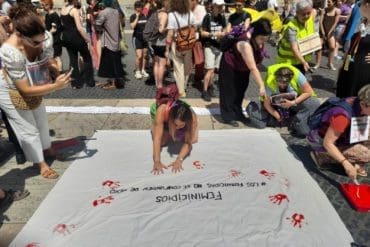 Women gathered on the streets leaving handprints on the banner "No Feminicidios" (Say no to murdering women )