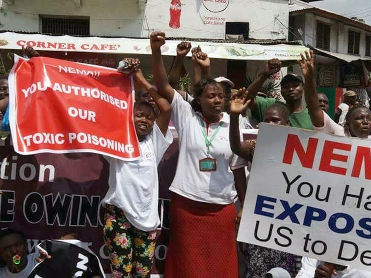 Phyllis Omido stands with her arms in the air while surrounded by Kenyan protesters.